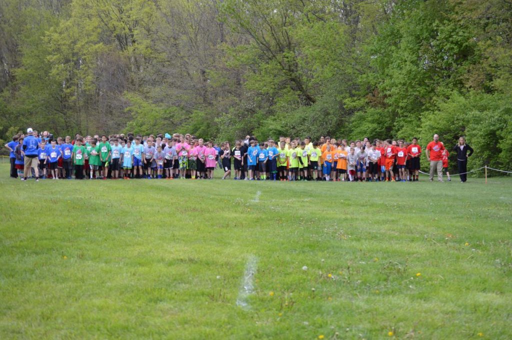 People standing on grass in a line, ready for a race.