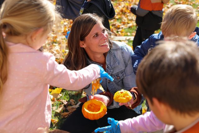 teacher shows students inside of a carved pumpkin