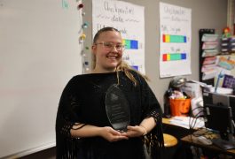 Woman holding a trophy in front of a classroom setting.